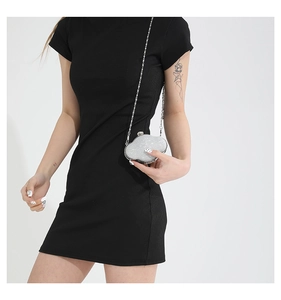 Detail of a black bodycon dress with vertical rib textures and a silver chain bag
