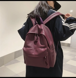 Detail of burgundy pebbled leather backpack showing the premium texture and front pocket