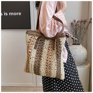Detail shot of woven straw tote bag with brown leather straps shown on model shoulder
