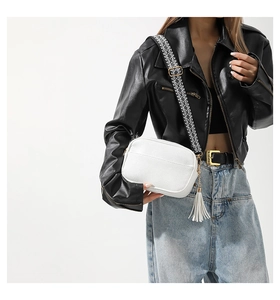 Detail of white pebbled leather bag with geometric strap and decorative leather tassel