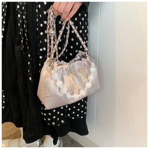 Vue détaillée du sac bourse en soie rose avec broderies florales et chaîne de perles