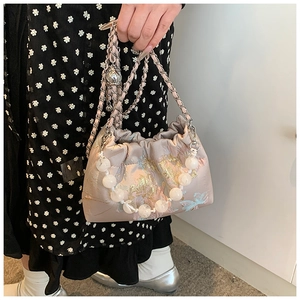 Détail du sac bandoulière en soie avec broderie florale, poignée perle et bandoulière chaîne