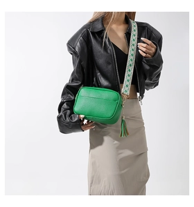 Green pebble leather crossbody bag detail with patterned wide strap and decorative tassel