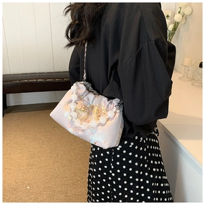 Détail du sac bandoulière en satin rose avec broderie florale et poignée en perles