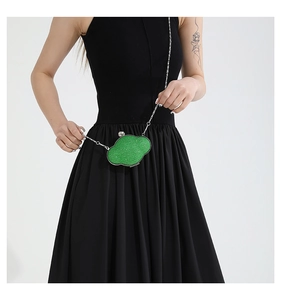 Detailed view of sparkly green sequin cloud bag with silver chain worn by a model