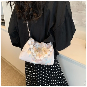 Détail du sac bandoulière en soie rose avec broderies florales et poignée en perles