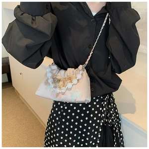 Détail d'un sac plissé rose clair avec broderie florale et bandoulière en perles