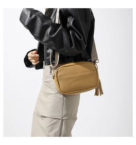 Detail of yellow pebbled leather crossbody bag with fringe tassel and woven strap