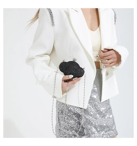 Detail of black glitter cloud clutch bag with silver chain strap on model in white suit