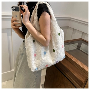 Detailed view of white faux shearling tote bag with colorful embroidered flower patterns
