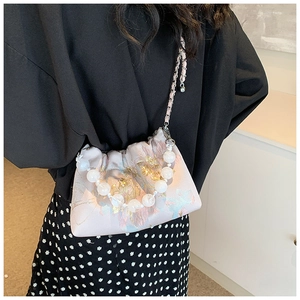 Détail du sac bandoulière en soie florale avec motifs dorés et poignée en perles