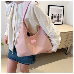 Detail showing pink leather underarm tote bag with logo on wooden counter scene