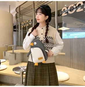 Detail der süßen Pinguin-Umhängetasche, getragen von einem Modell in einem gemütlichen Café