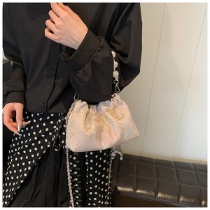 Détail du sac nuage en soie rose avec broderie florale, poignée perle et chaîne argent