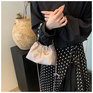 Détail de broderies florales et paillettes dorées sur un sac seau en soie avec perles