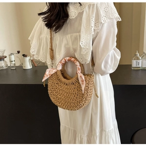Detail of hand-woven straw crescent bag with floral scarf handle and detachable strap