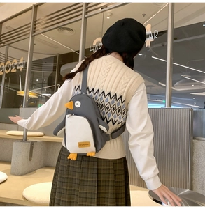 Detailansicht eines süßen Pinguin-Rucksacks aus grauem Canvas mit gelben Akzenten am Model