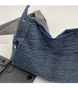 Detail of blue denim handbag with knot strap on a grey blazer and decor card