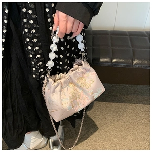 Vue détaillée d'un sac en soie rose avec broderie florale et anse en perles