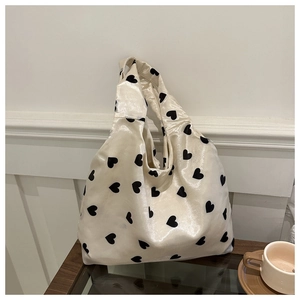 Minimalist cream tote bag with black heart pattern in a cozy cafe setting scene