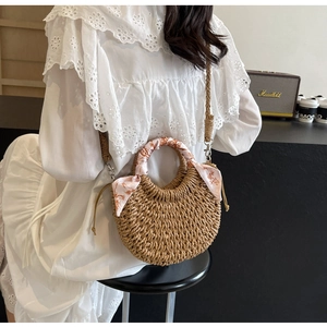 Detail view of woven crescent handbag with silk scarf handle and crossbody strap