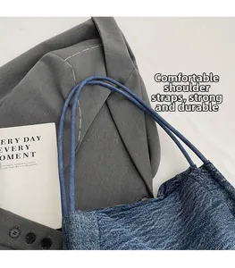 Close-up of durable denim tote bag straps and texture on a grey suit background