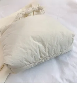 Détail du sac fourre-tout nuage en nylon matelassé blanc cassé avec poignée à froufrous