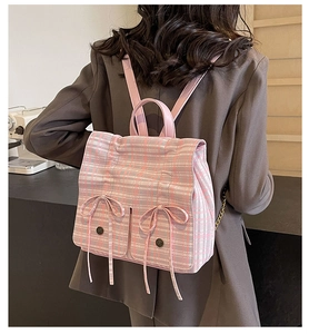 Rear view of a model wearing a pink plaid backpack with ribbon bows and leather straps