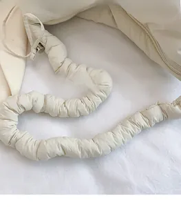 Détail du sac matelassé blanc montrant la bandoulière souple avec cordon de serrage froncé