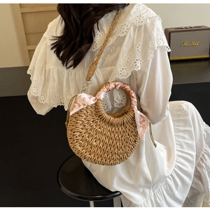 Detail of woven crescent crossbody bag with floral silk scarf handle and long strap