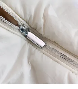 Gros plan sur la fermeture éclair argentée et le tissu en nylon blanc d'un sac bandoulière