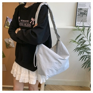 Detailed close-up of a large light grey nylon slouchy crossbody bag worn by a model
