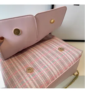 Detail of pink plaid bag featuring gold magnetic buckles and polished chain strap