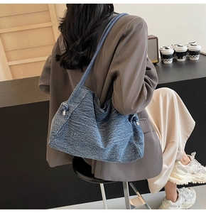 Detail of blue denim tote bag with knot strap shown in a modern lifestyle setting