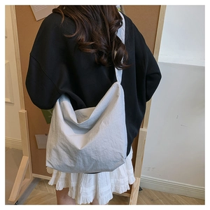 Detailed back view of a minimalist large grey nylon crossbody bag on a female model