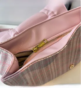 Detail view of the smooth metal zipper and pink leather texture on a bow handbag