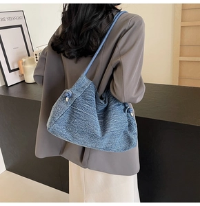 Close-up of blue denim tote bag with side knot details worn by model in studio