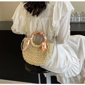 Detail of beige woven straw moon bag with silk scarf handle and drawstring closure