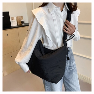 Détail du grand sac bandoulière en nylon noir avec une texture plissée de style moderne