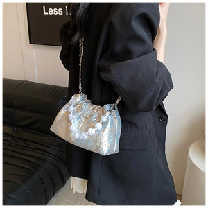 Sac bandoulière en soie avec poignée en perles et texture jacquard argentée sur blazer noir