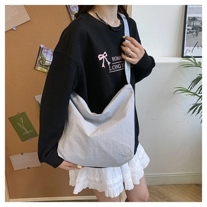 Lifestyle shot of large light grey nylon crossbody bag for women in casual home setting