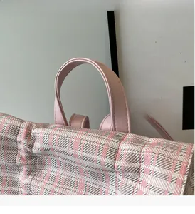 Close-up of pink checkered fabric backpack featuring durable faux leather top handle