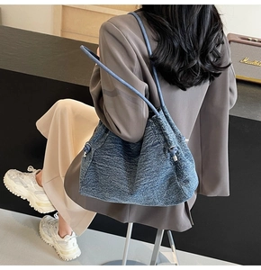 Detail of blue denim tote bag with thick rope straps and metal ring attachments