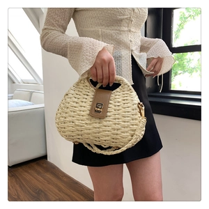 Handwoven half-moon crossbody bag with leather flap and metal lock in minimalist style