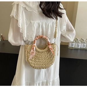 Detail of woven straw half-moon bag with floral silk scarf and long shoulder strap