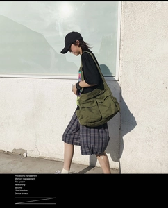 Detail view of army green canvas crossbody bag featuring large front flap pockets and durable fabric