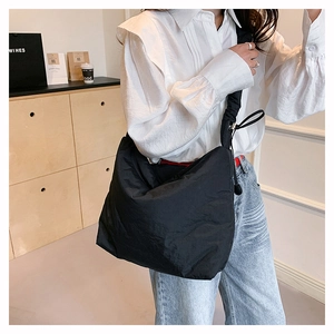 Détail d'un sac bandoulière en nylon noir avec texture plissée et cordon de serrage réglable