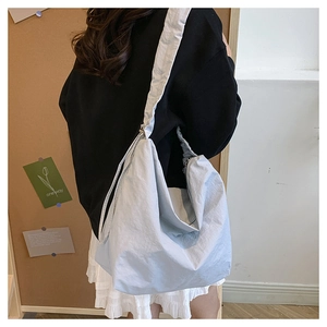 Close-up of light blue nylon crossbody bag featuring smooth zipper and wide shoulder strap