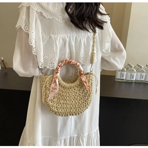 Detail of hand-woven straw crossbody bag with printed silk scarf wrap on handle