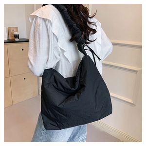 Vue arrière du modèle portant un grand sac bandoulière matelassé noir en nylon style nuage